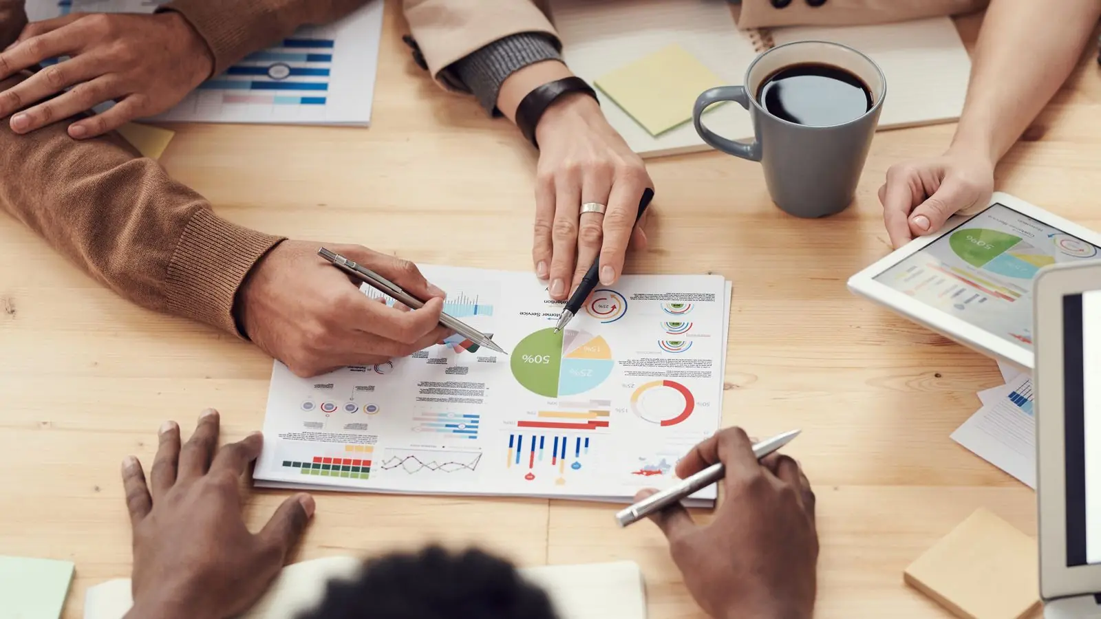 Printed charts and a laptop dashboard on a meeting table
