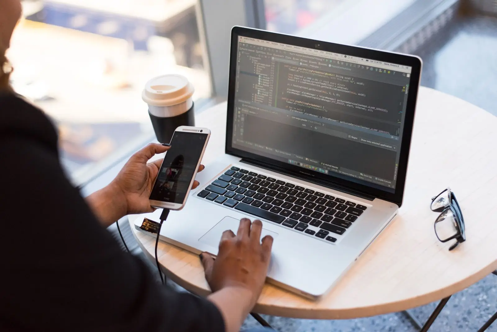 Laptop showing code next to a coffee cup