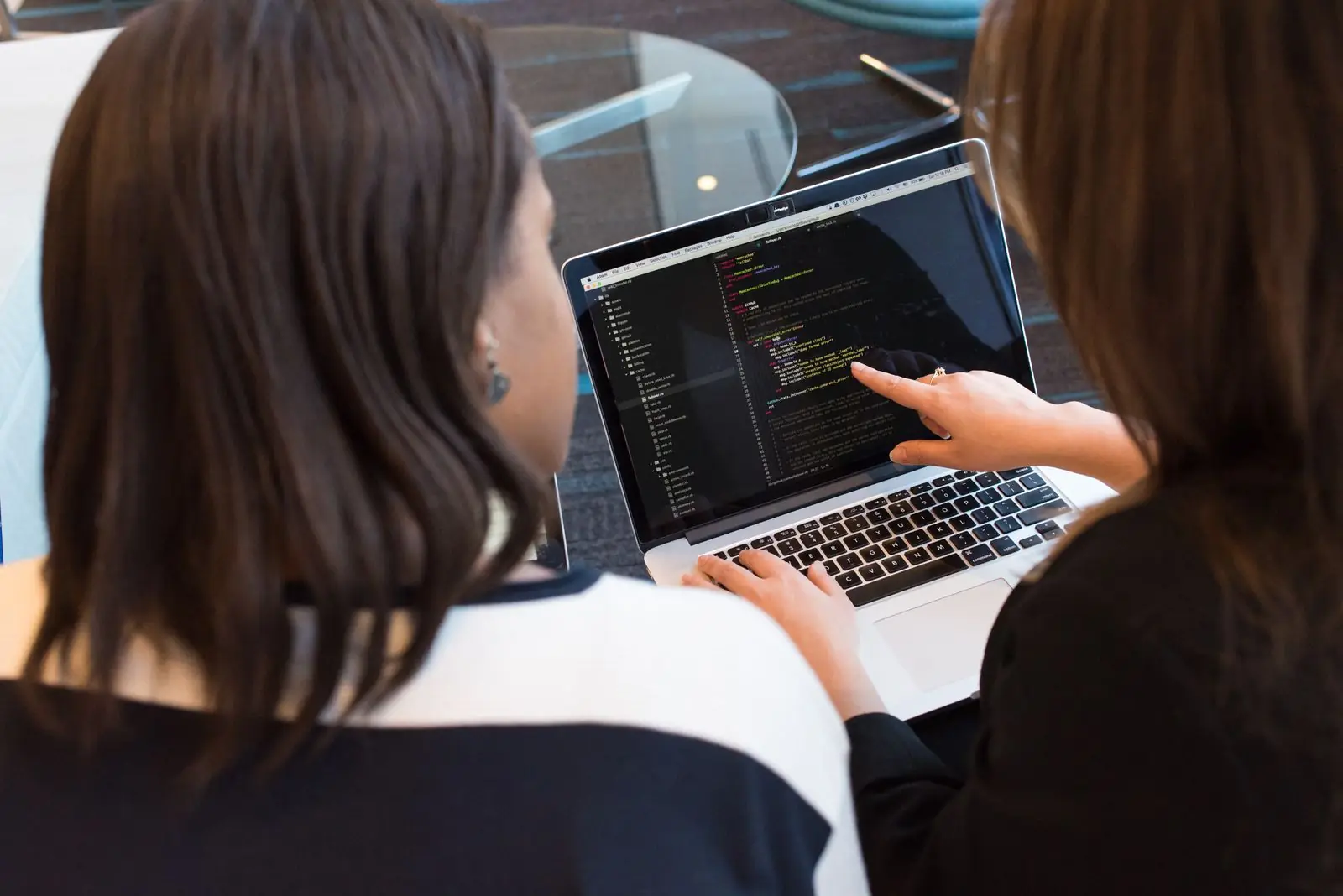 Two engineers pairing on code at a shared laptop